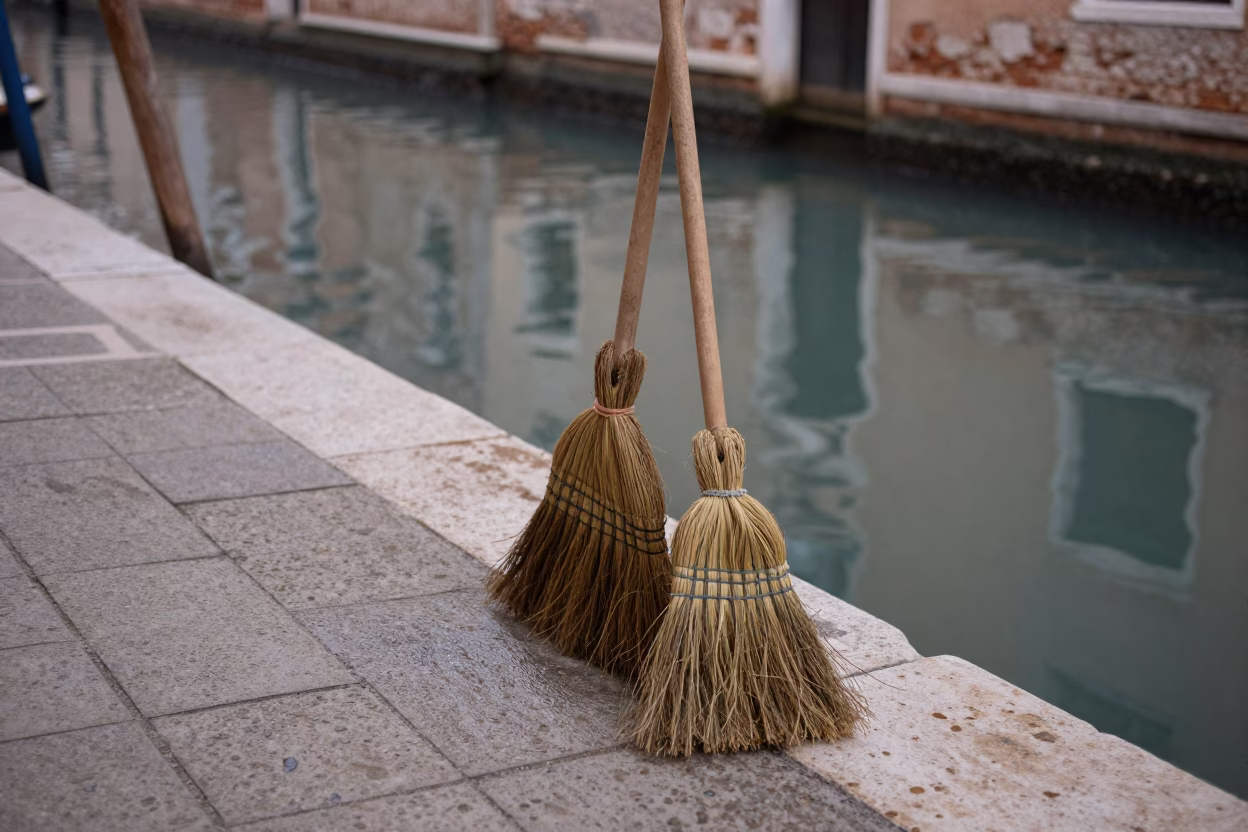 Early Morning Venice Canal Scene with Wooden Brooms Leaning Against Ancient Stone Walls in in Venice, Italy