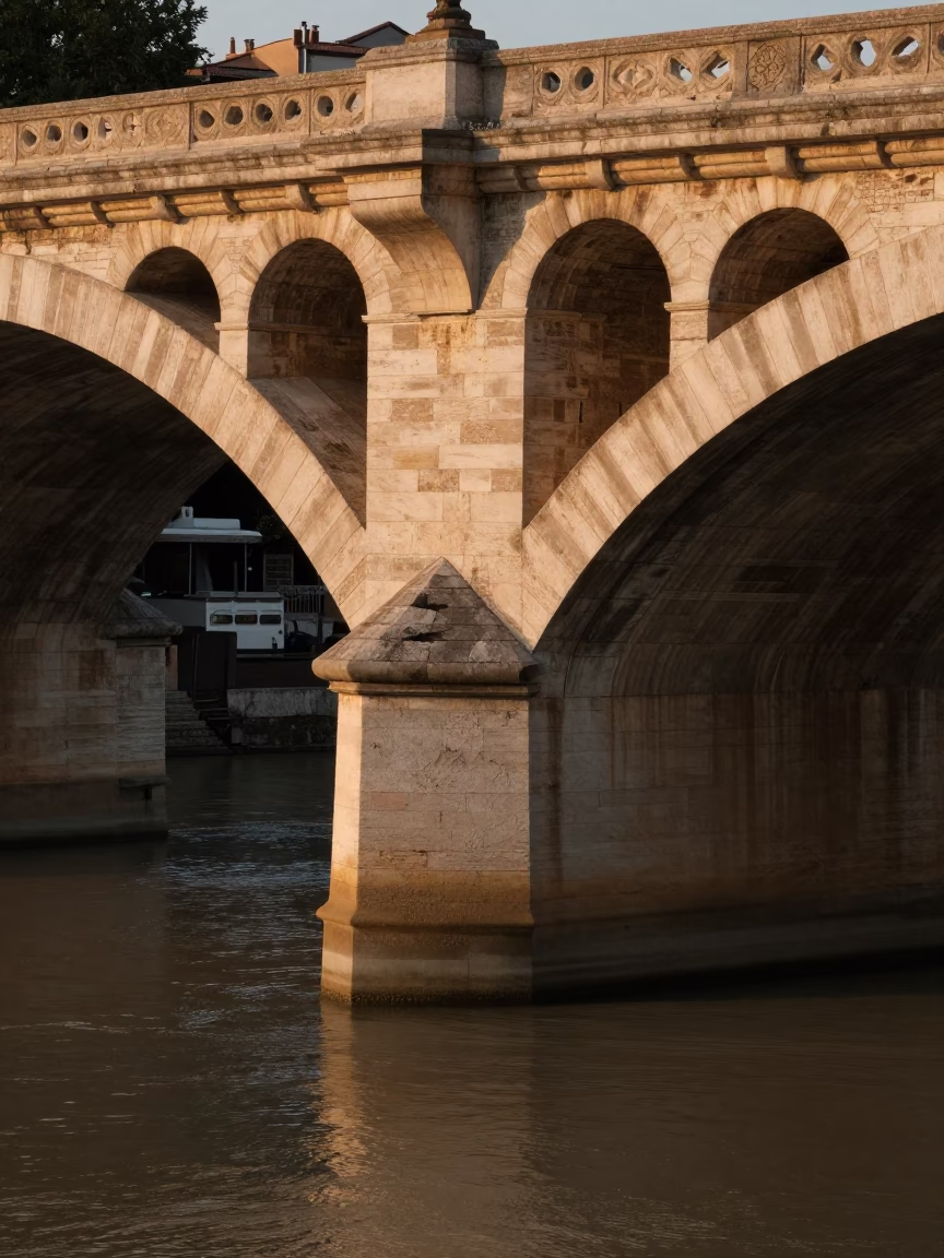 Evening light illuminates historic Lyon France bridge pier splitting brown river current in in Lyon, France