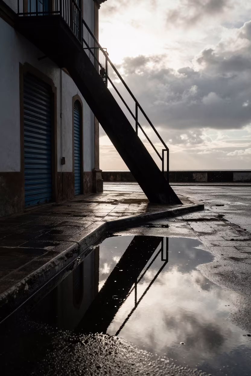 Fire Escape Reflection in Nampula Puddle in along a shuttered arcade in Nampula