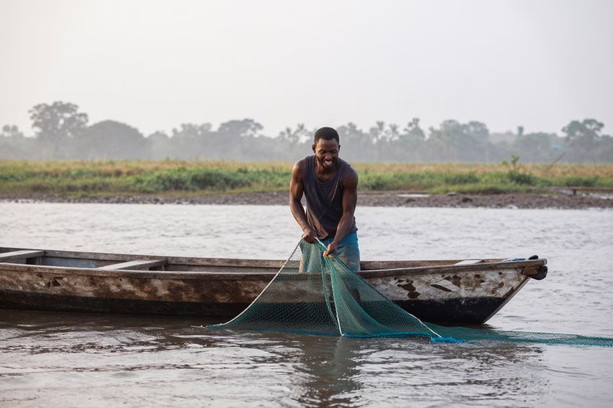 Fisherman Hauls Net from Wooden Dory at Dawn in near open fields near Huambo