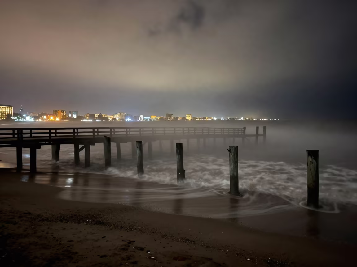 Fog Swallows Pier Posts Near City Lights in over a horizon of stacked thunderheads near Ciudad de la Costa