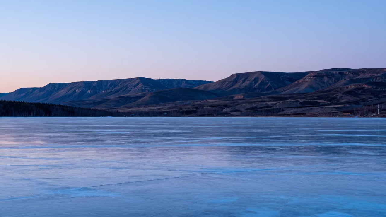 Frozen Tundra Lake Under Arctic Twilight Sky in from a ridge above layered foothills in Canada