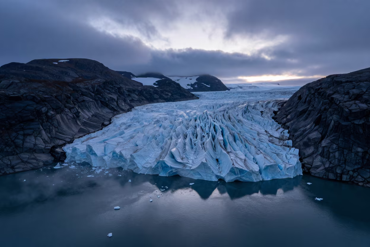 Glacier Calving into Fjord at Twilight in from a ridge above layered foothills in Russia