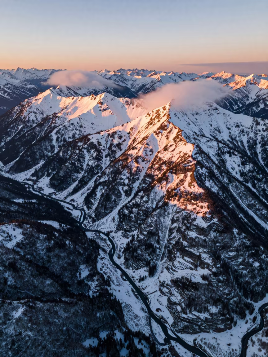 Golden Hour Aerial View of BC Snow Mountains in high above braided river channels in British Columbia