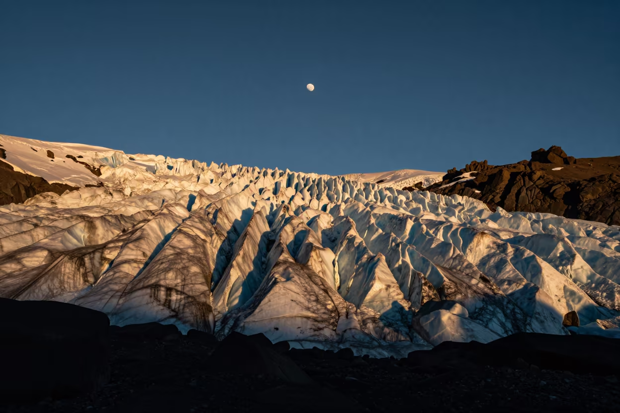 Golden Sun and Rising Moon Light a Silver Glacier Face in beneath a dark-sky overlook in Iceland
