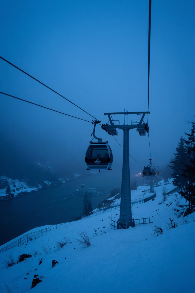 Gondola Emerging from Fog Above River at Twilight in beside a lift tower above corduroy snow near Innsbruck