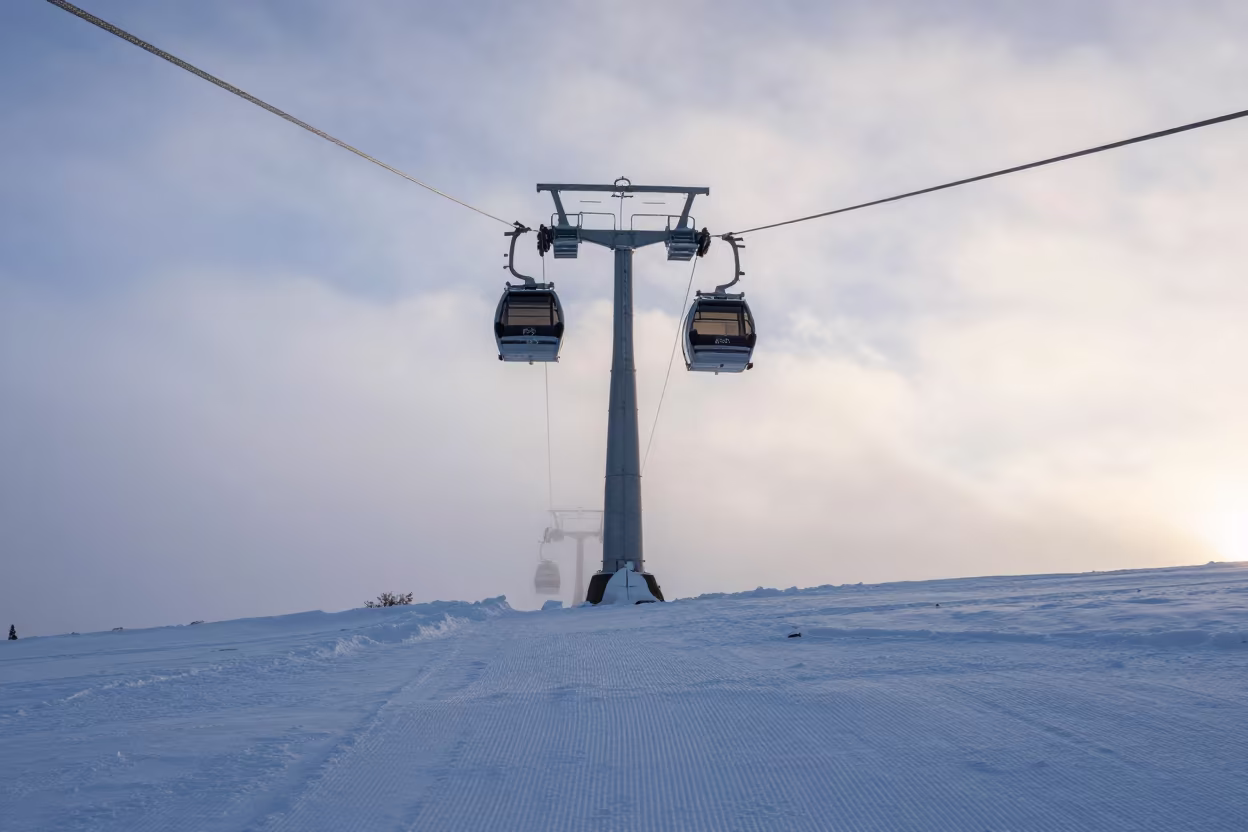 Gondola Lift Rising Over Corduroy Snow in Mist in beside a lift tower above corduroy snow near Sapporo