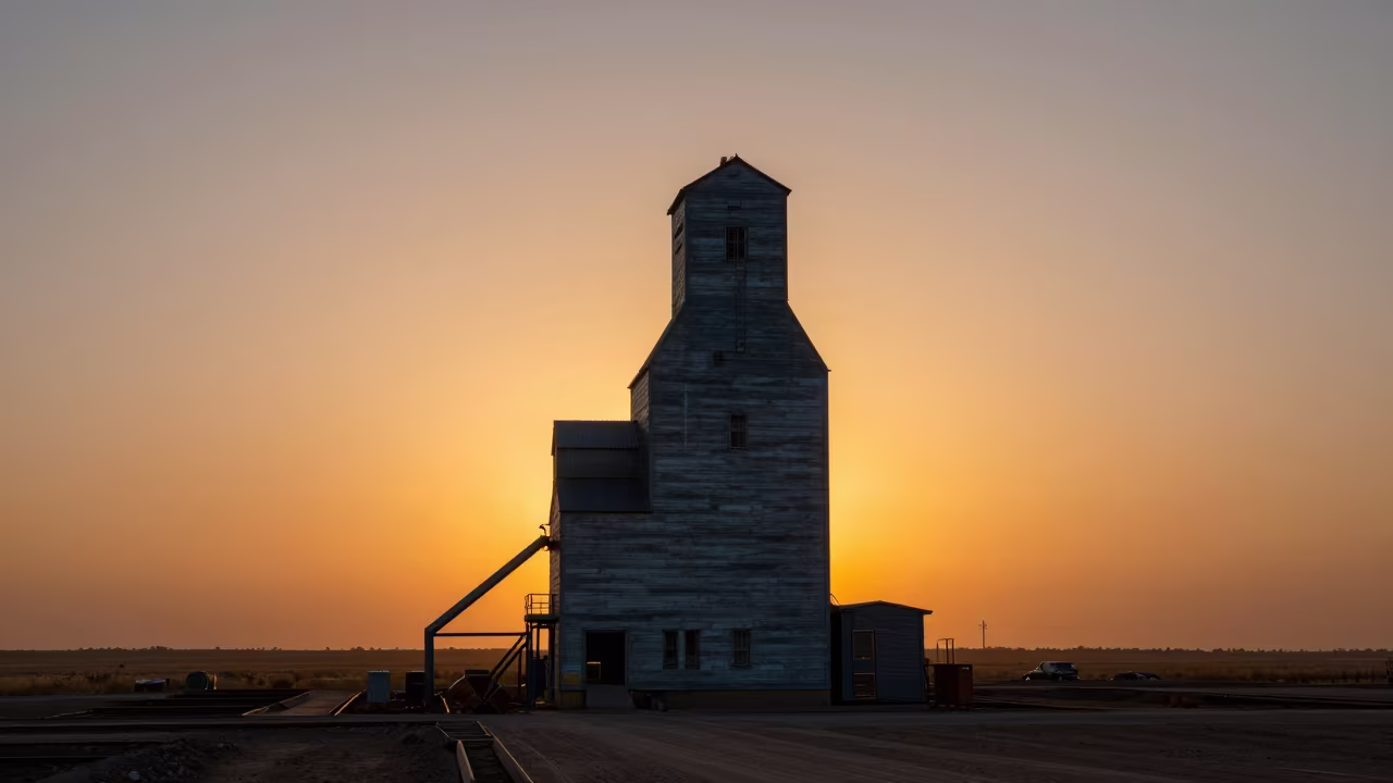 Grain Elevator Silhouette Against Prairie Sunset in across an active works site near Shiraz