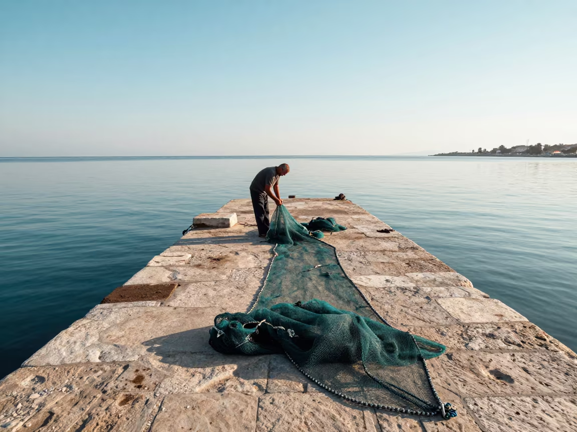 Greek Fisherman Untangling Seine Net at Lanzhou Harbor in at a harbor quay near Lanzhou