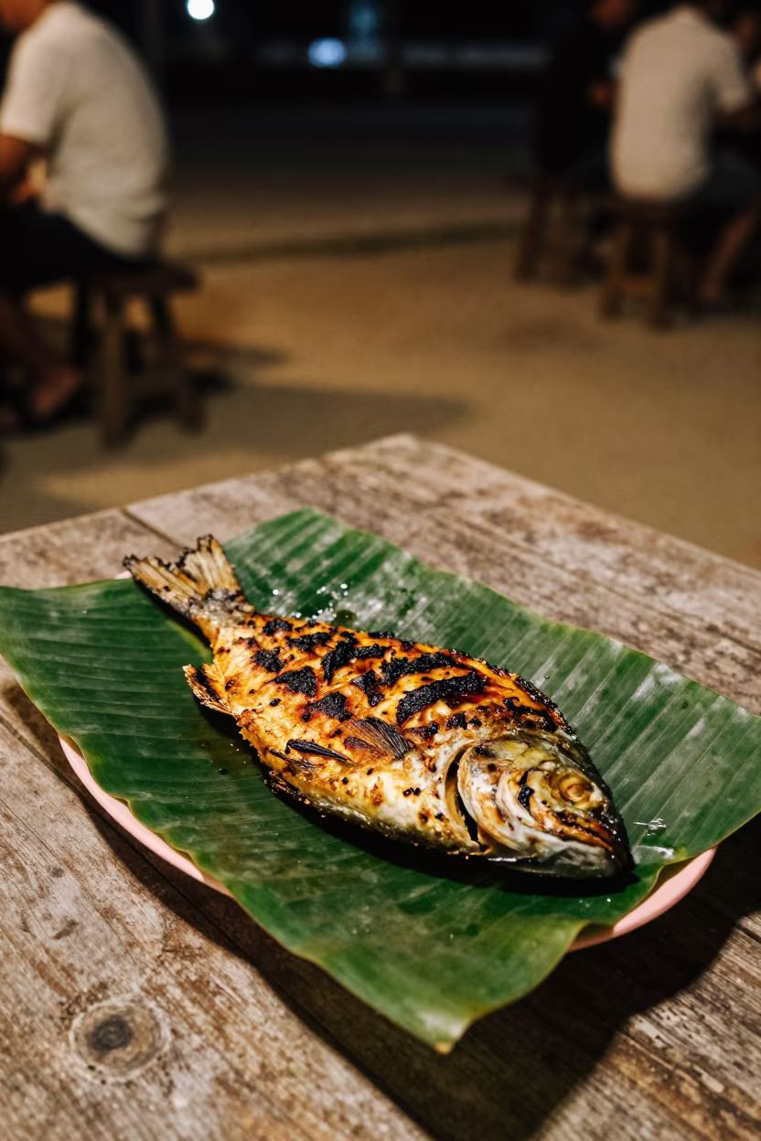 Grilled Fish on Banana Leaf at Night in on a weathered outdoor table near Kuala Lumpur