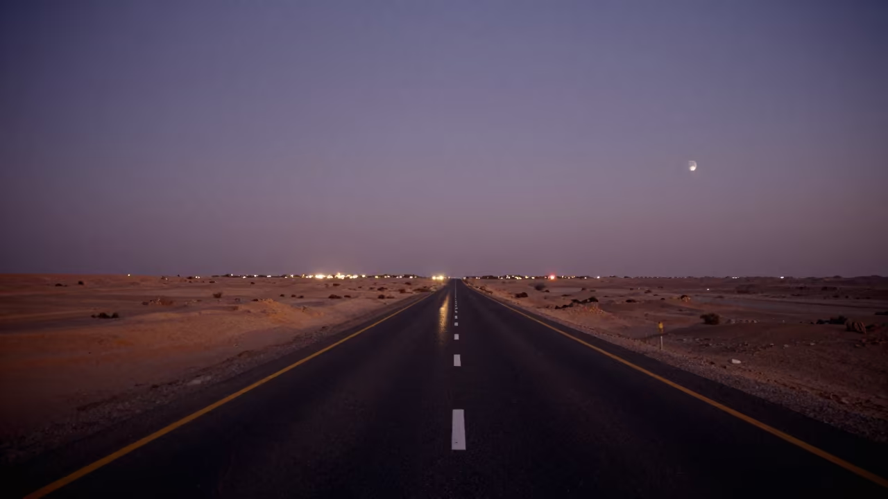 Half Moon Over Desert Highway at Dusk in beneath a moon-washed horizon in Saudi Arabia