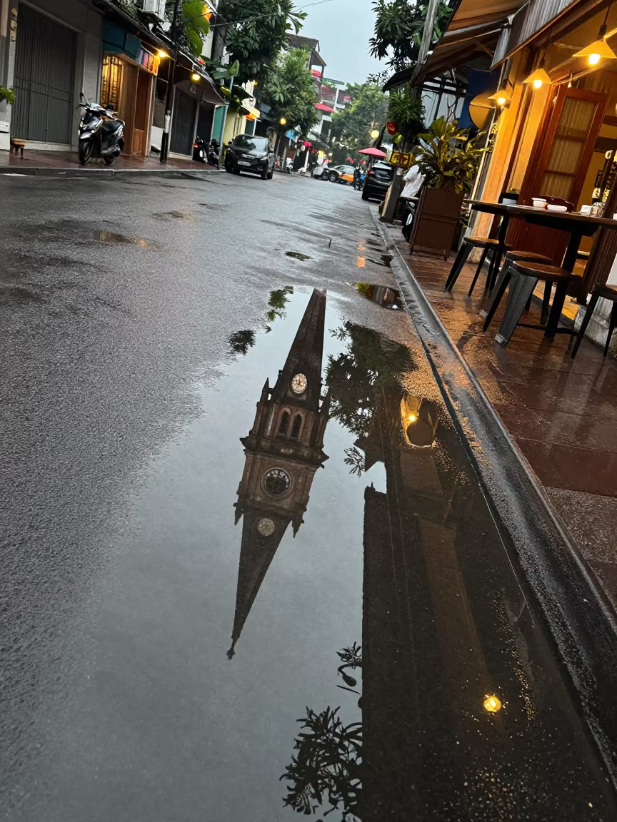 Hanoi Street Puddle Reflection Church Steeple in outside a corner cafe in Hanoi