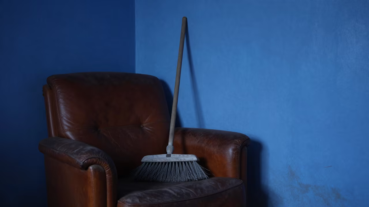 Hearth Broom on Leather Armchair in Maiduguri Twilight in on a worn leather armchair near Maiduguri