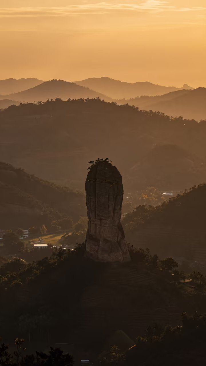 Hoodoo Spire Silhouette Against Amber Sunset Sky in from a ridge above layered foothills in Singapore
