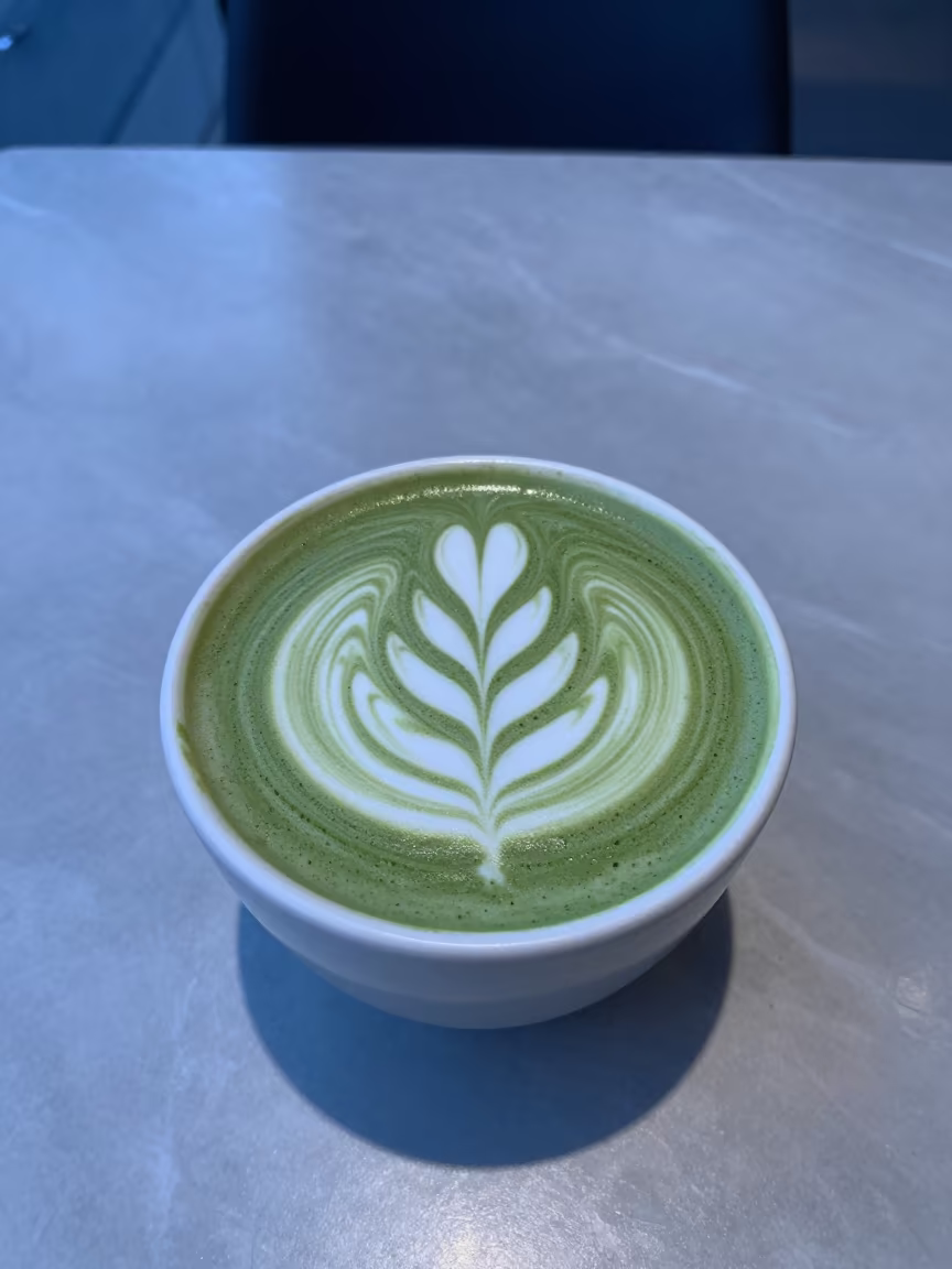 Indigo Twilight Matcha Latte with Foam Art in on a marble cafe table in Phoenix