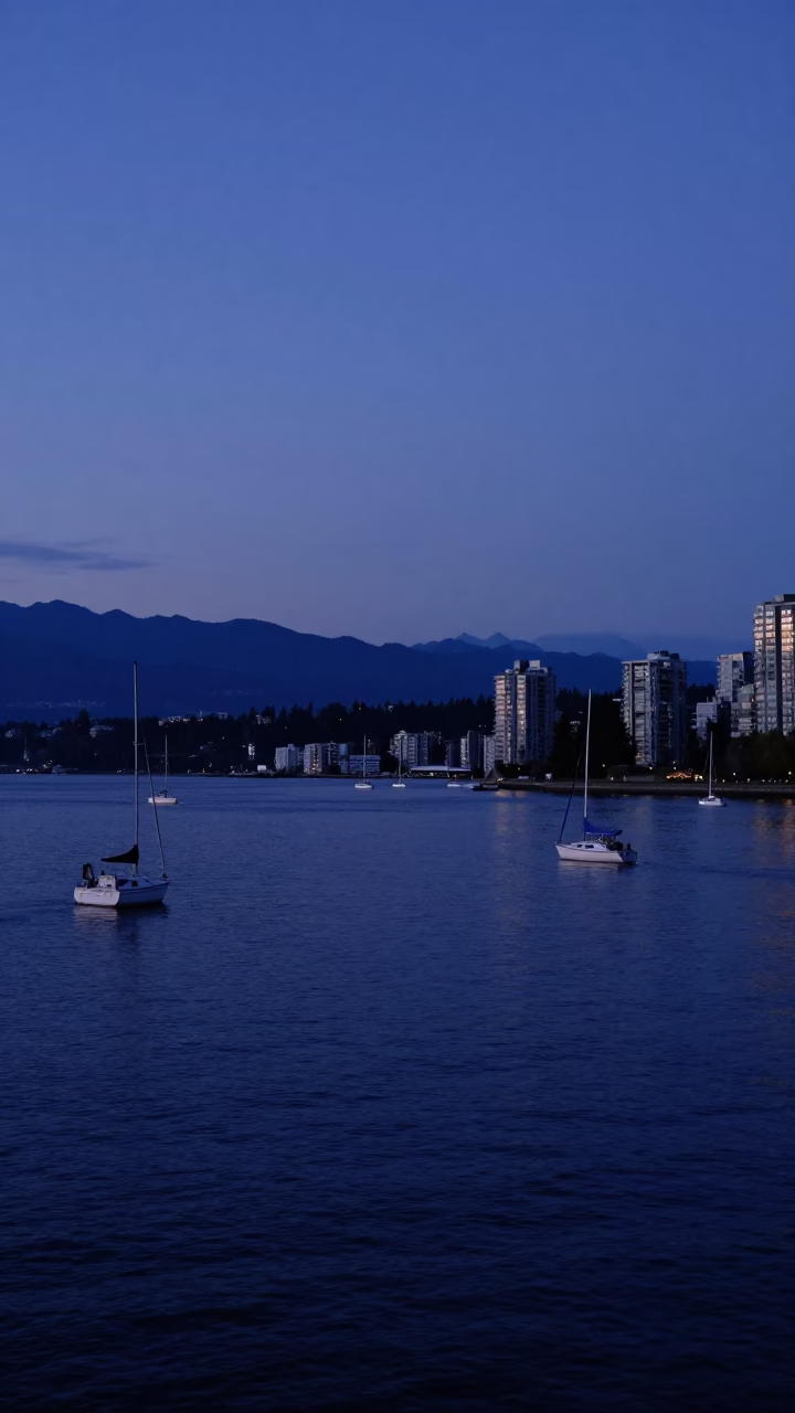 Indigo twilight over Vancouver harbor with distant sailboats and city skyline lights in in Vancouver, British Columbia, Canada