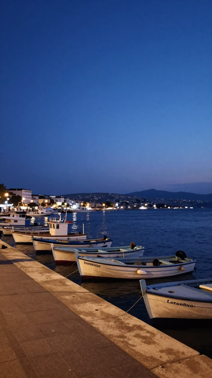 Izmir Turkey indigo twilight harbor scene with fishing boats and distant lighthouse beam in in Izmir, Turkey