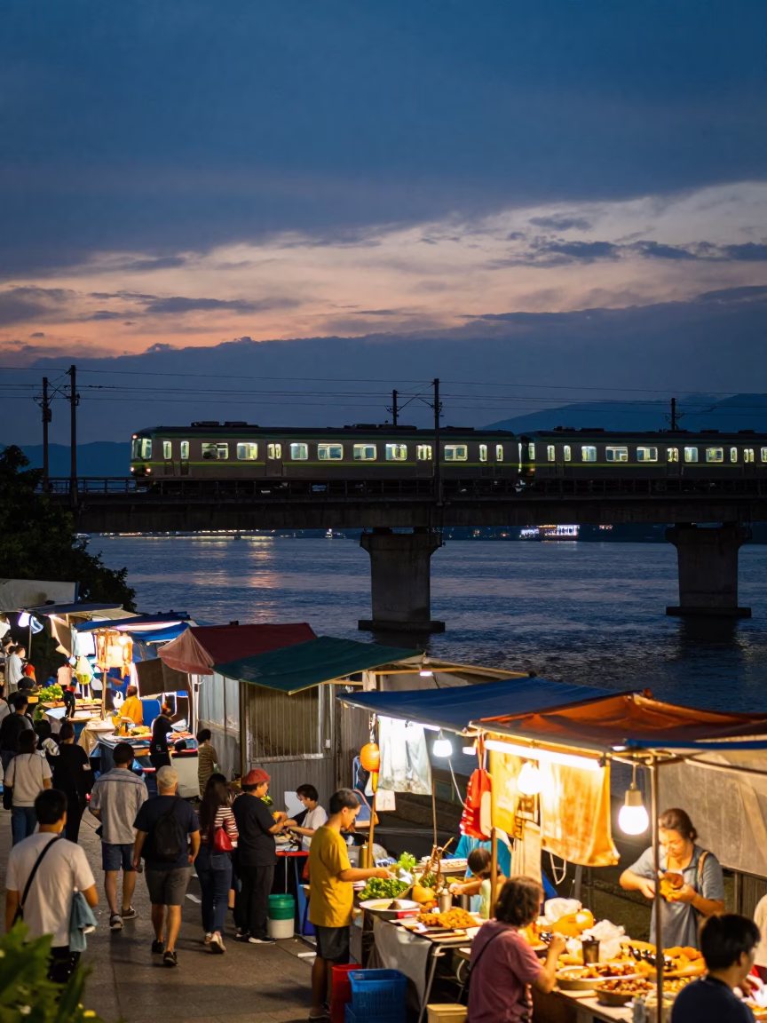 Kaohsiung Twilight Street Scene with Commuter Train Crossing Bridge and Local Vendor in in Kaohsiung, Taiwan