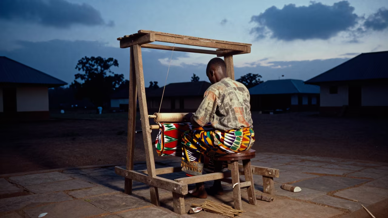 Kente Weaver in Kumasi Temple Courtyard at Blue Hour in in a temple courtyard in Kumasi
