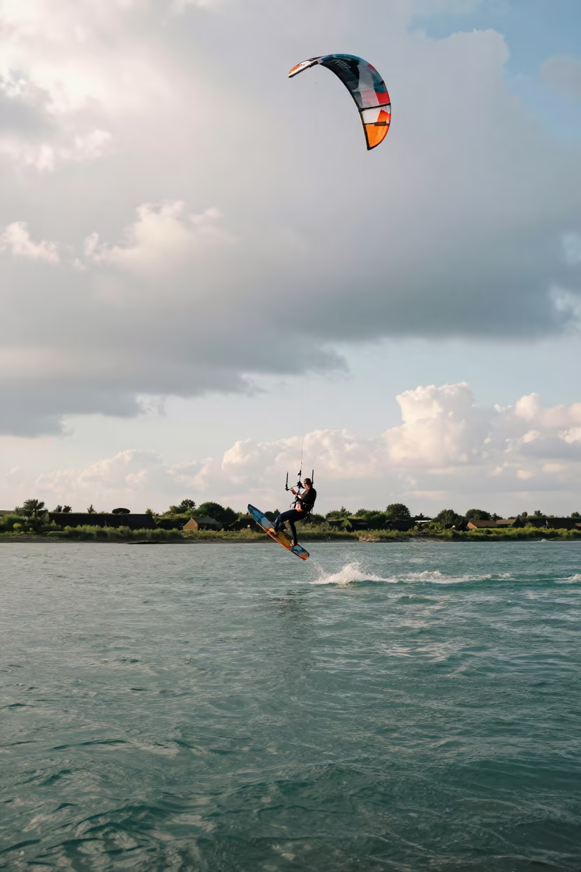 Kitesurfer Boosting High Over Turquoise River Water in by a riverbank near Wenzhou