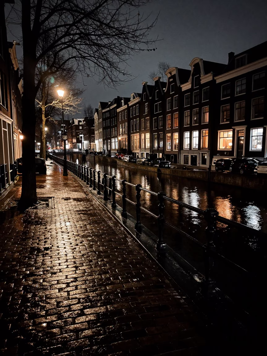 Late Night Amsterdam Canal Side Street Scene with Wet Pavement and Urban Reflections in in Amsterdam, Netherlands
