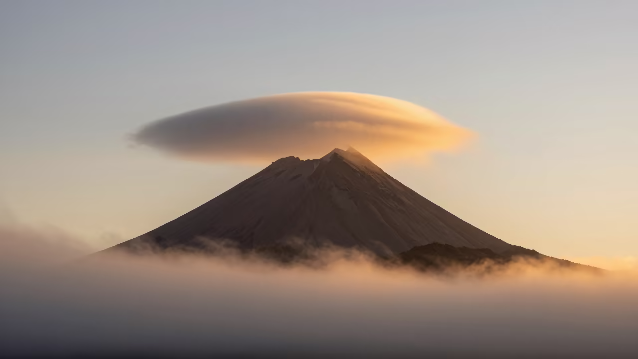 Lenticular Cloud Over Patagonian Volcano Golden Hour in through low marine fog in Patagonia