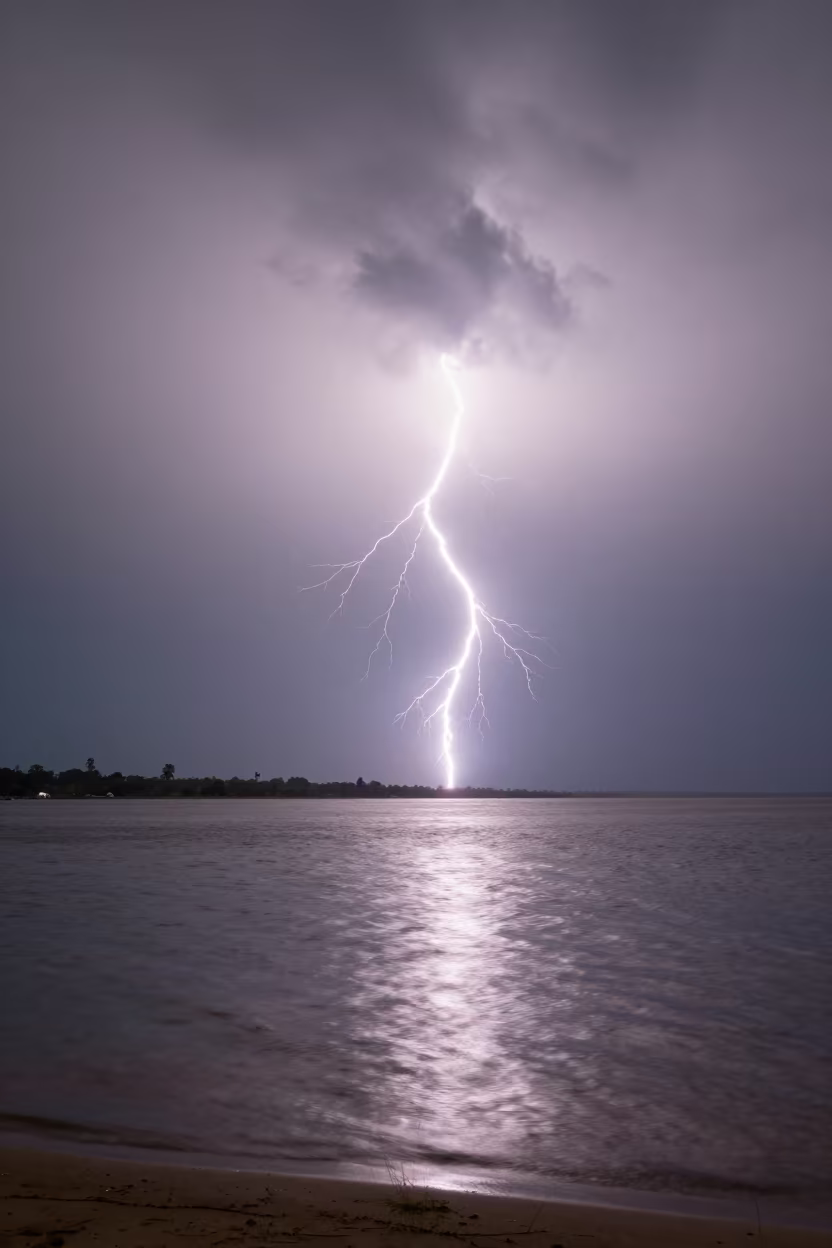 Lightning Striking Rippled Lake Under Clouds in beneath fast-moving cloud bands in Equatorial Guinea