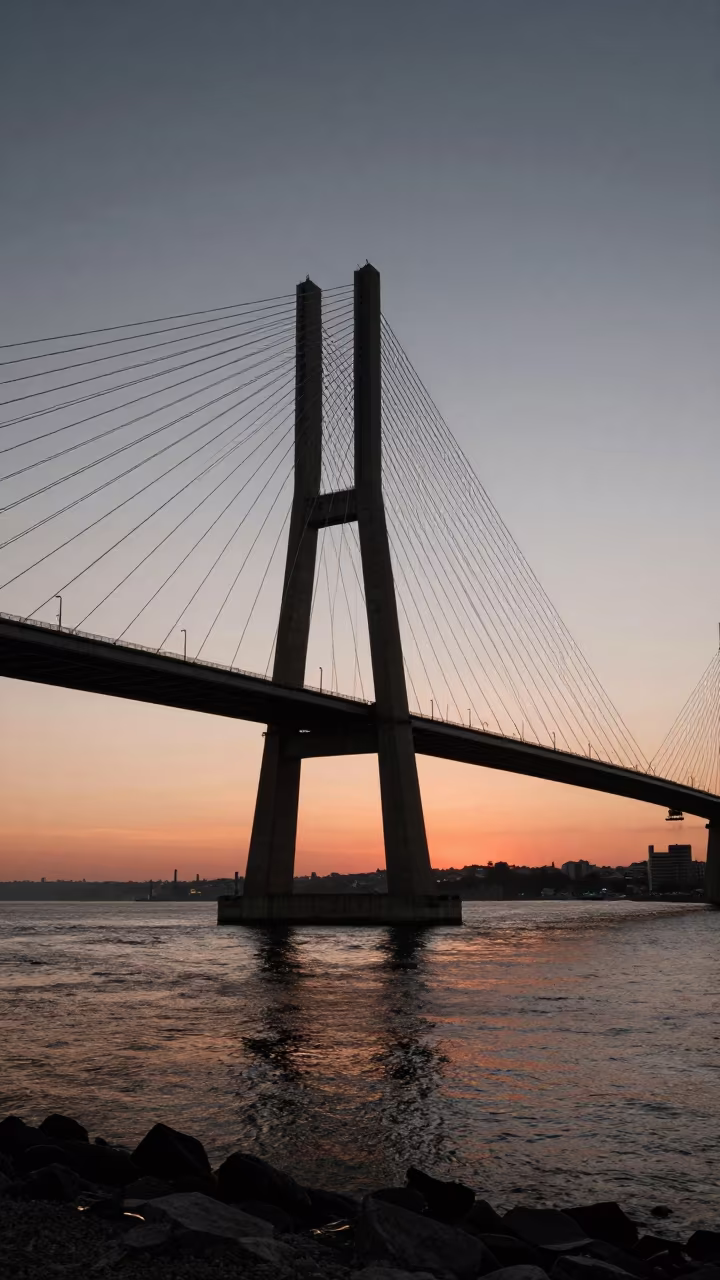 Lisbon Cable Bridge Golden Hour Harbor Glow in beneath a bridge span in Lisbon