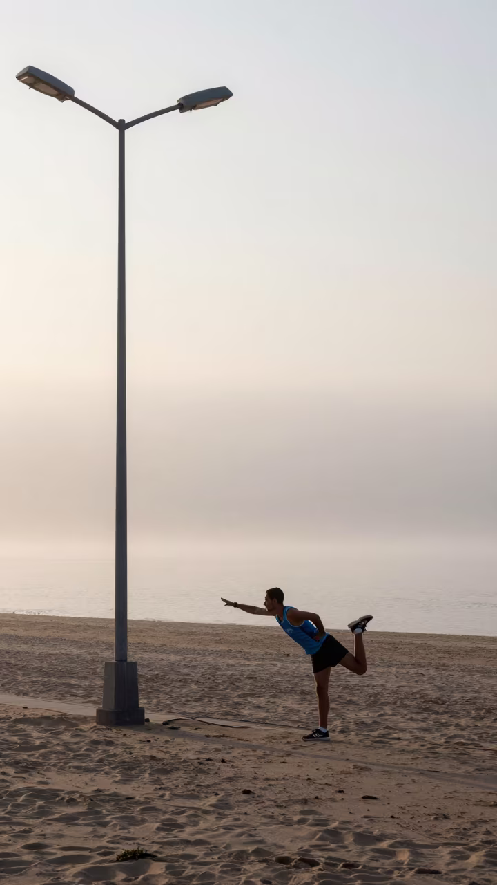 Marathon Runner Stretching Under Streetlamp at Dawn in along a beach near Najaf