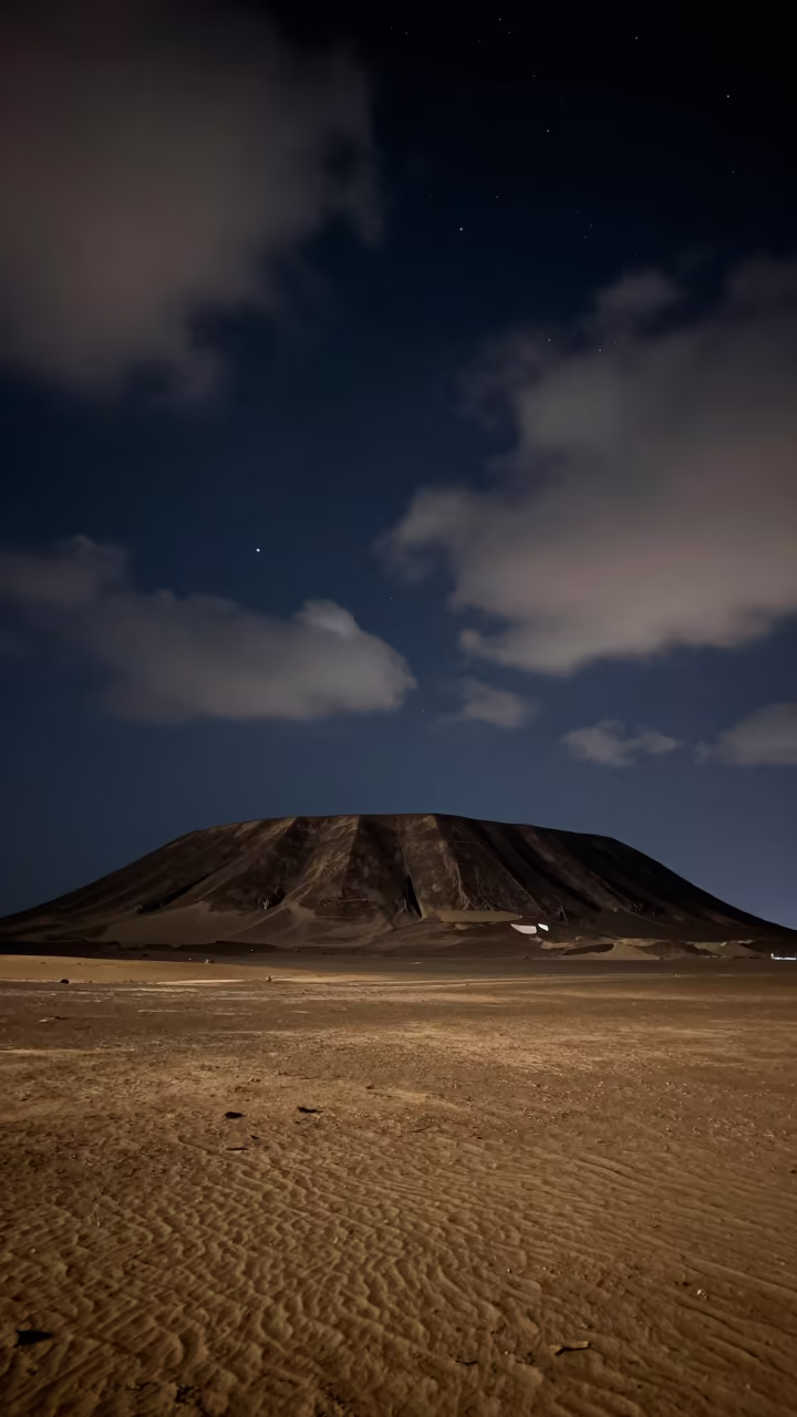Meteor Crater Silhouette Under Starry Egyptian Night in beneath thin cloud gaps and stars in Egypt