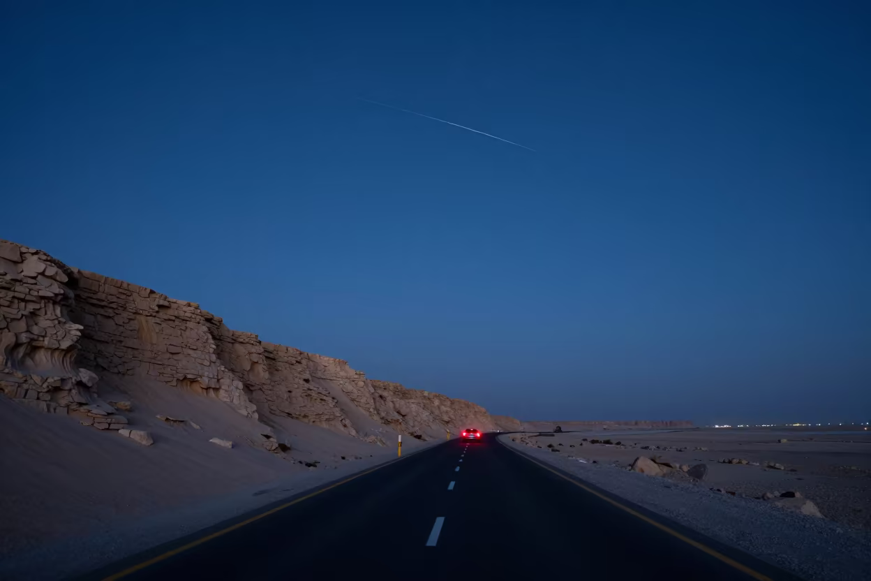 Meteor Streaking Over Doha Desert Road Night in beneath a wind-cut desert escarpment near Doha