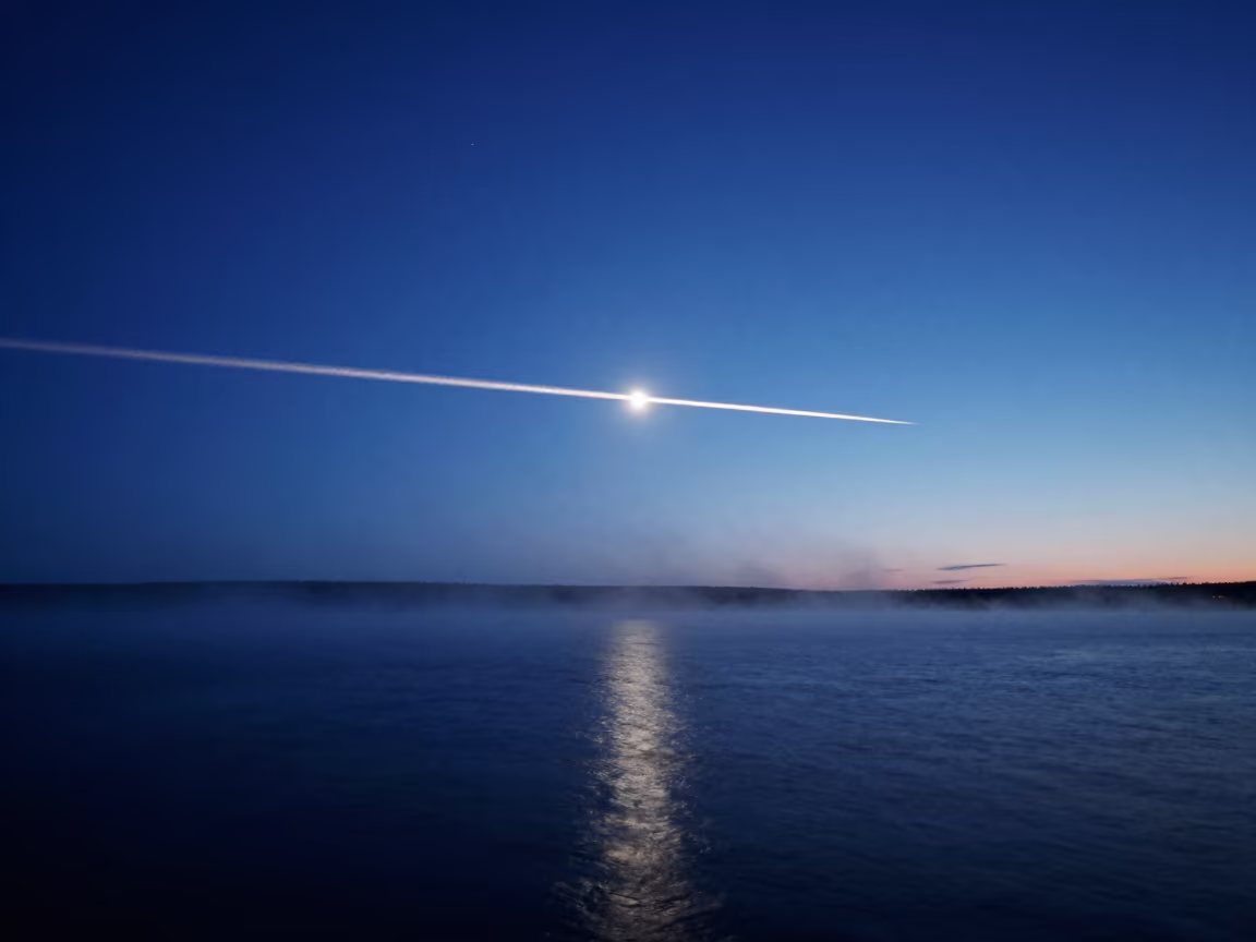 Meteor Trail Over Misty Northwest Territories Water in beneath a moon-washed horizon in Northwest Territories