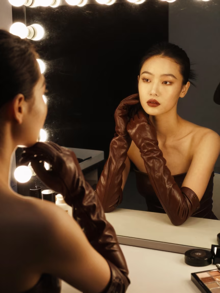 Model Pulls Gloves Under Mirror Bulbs Fuzhou in beside a mirror lined with makeup bulbs in Fuzhou