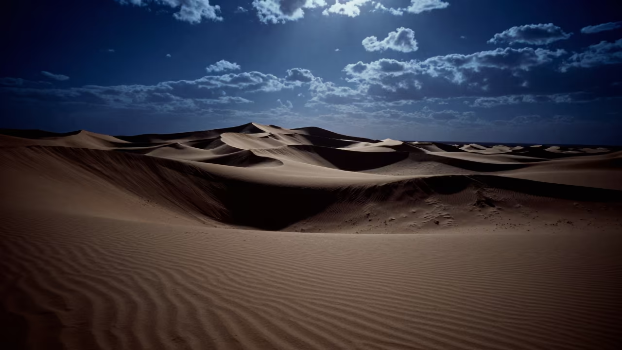 Moonlit Sand Dunes Under Iranian Escarpment in beneath a wind-cut desert escarpment in Iran