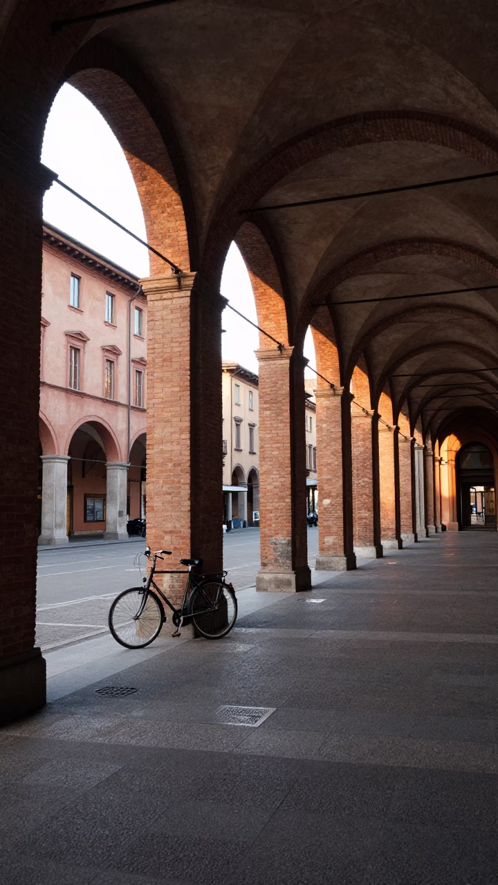 Morning light on Bologna porticoes with parked bicycle and majolica shop display in in Bologna, Italy