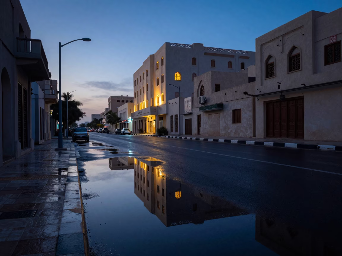 Muscat Oman Pre-Dawn Street Scene With Wet Puddle Reflections And Hotel Windows in in Muscat, Oman