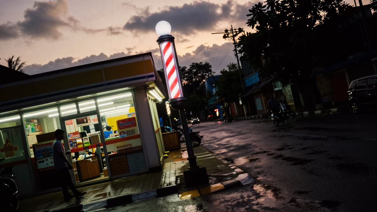 Neon Barber Pole Glows Over Wet Cumilla Street in outside a fluorescent convenience store in Cumilla