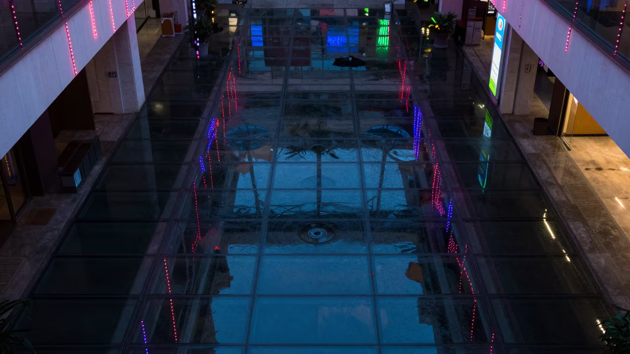 Neon Reflections on Wet Glass Atrium Floor in inside a vaulted atrium in Guiyang