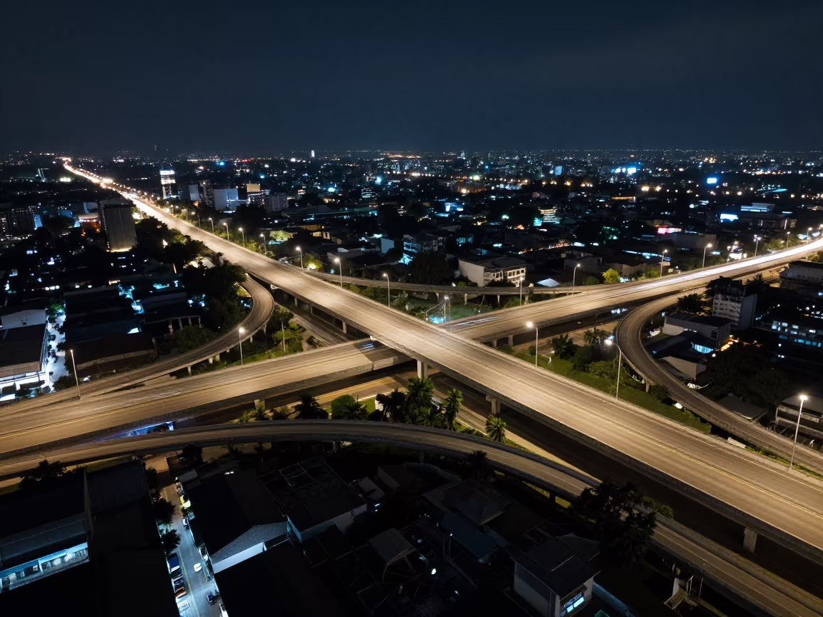 Night aerial highway interchange Thailand in high above patterned rooftops in Thailand