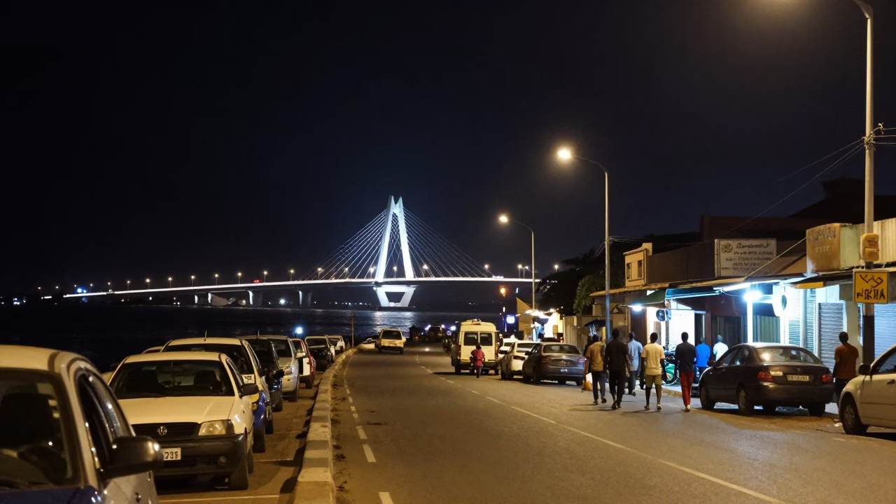 Nighttime Dakar Street Scene with Illuminated Bridge and Local Vendor Displaying Goods in in Dakar, Senegal