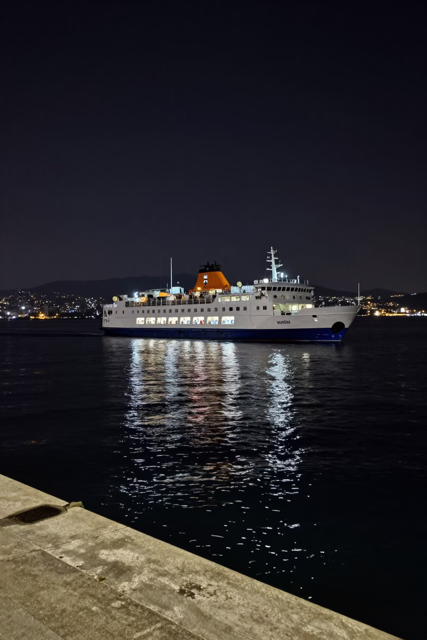 Nighttime Ferry Departure from Izmir Harbor with Distant Mountain Silhouettes and City Lights in in Izmir, Turkey