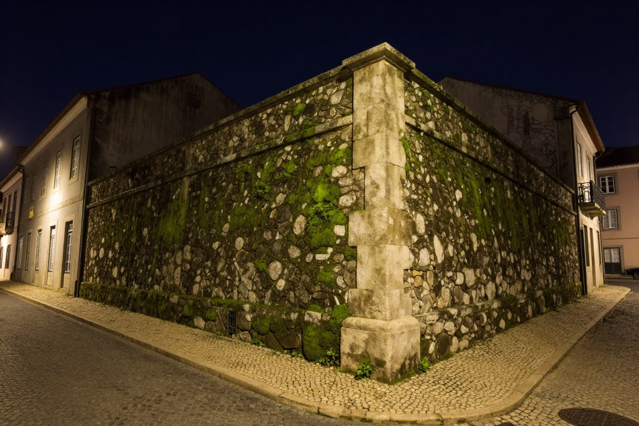Nighttime Lisbon Street Scene with Mossy Stone Wall and Leaf Shadows on Tile Grout in in Lisbon, Portugal