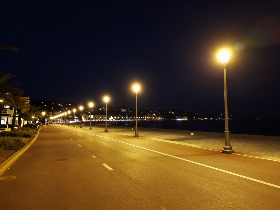 Nighttime Promenade des Anglais with glowing streetlights and coastal reflections in Nice France in in Nice, France