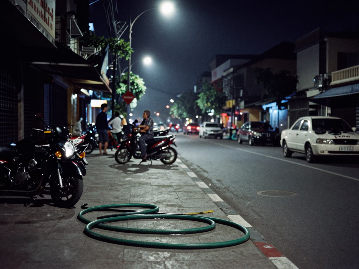Nighttime Street Scene in Ho Chi Minh City with Garden Hose and Concrete Sidewalk in in Ho Chi Minh City, Vietnam
