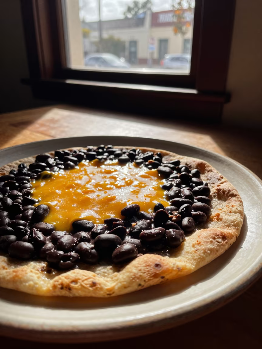 Oaxacan Tlayuda with Black Beans and Cheese in on a ceramic plate by a window in Silver Lake, Los Angeles