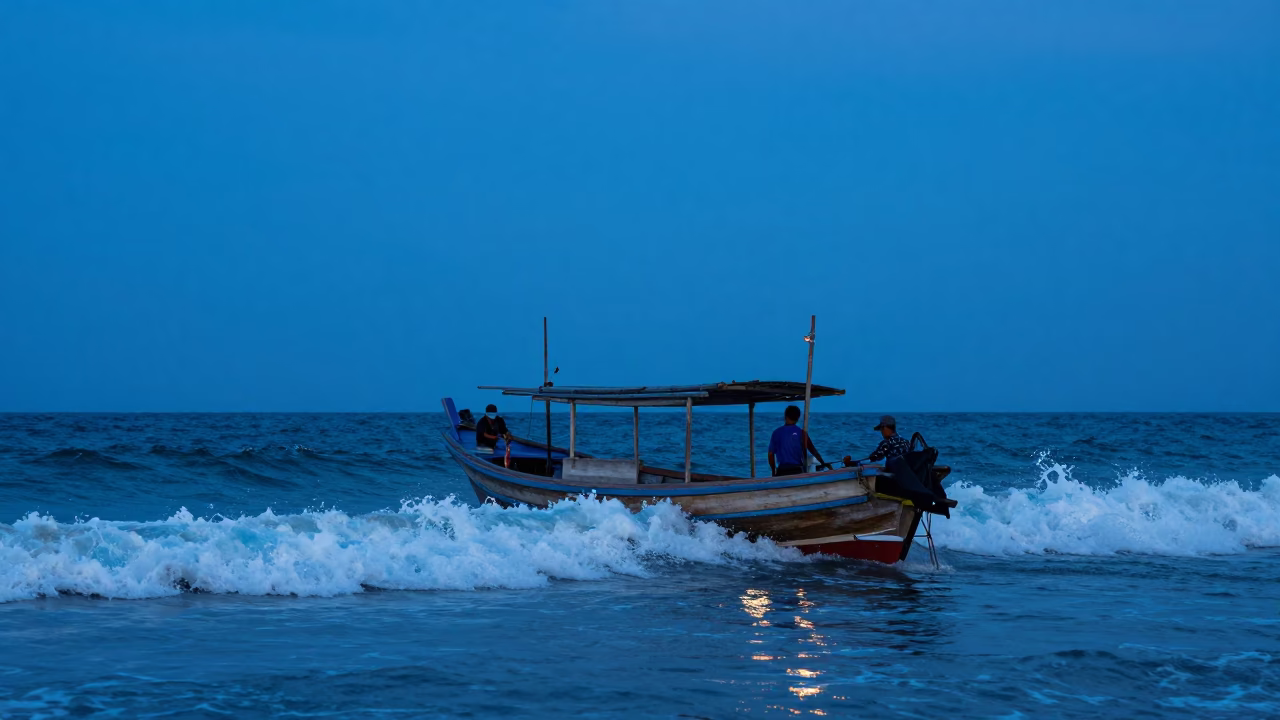 Phuket Thailand Evening Fishing Boat Returning Through Surf Under Blue Light in in Phuket, Thailand