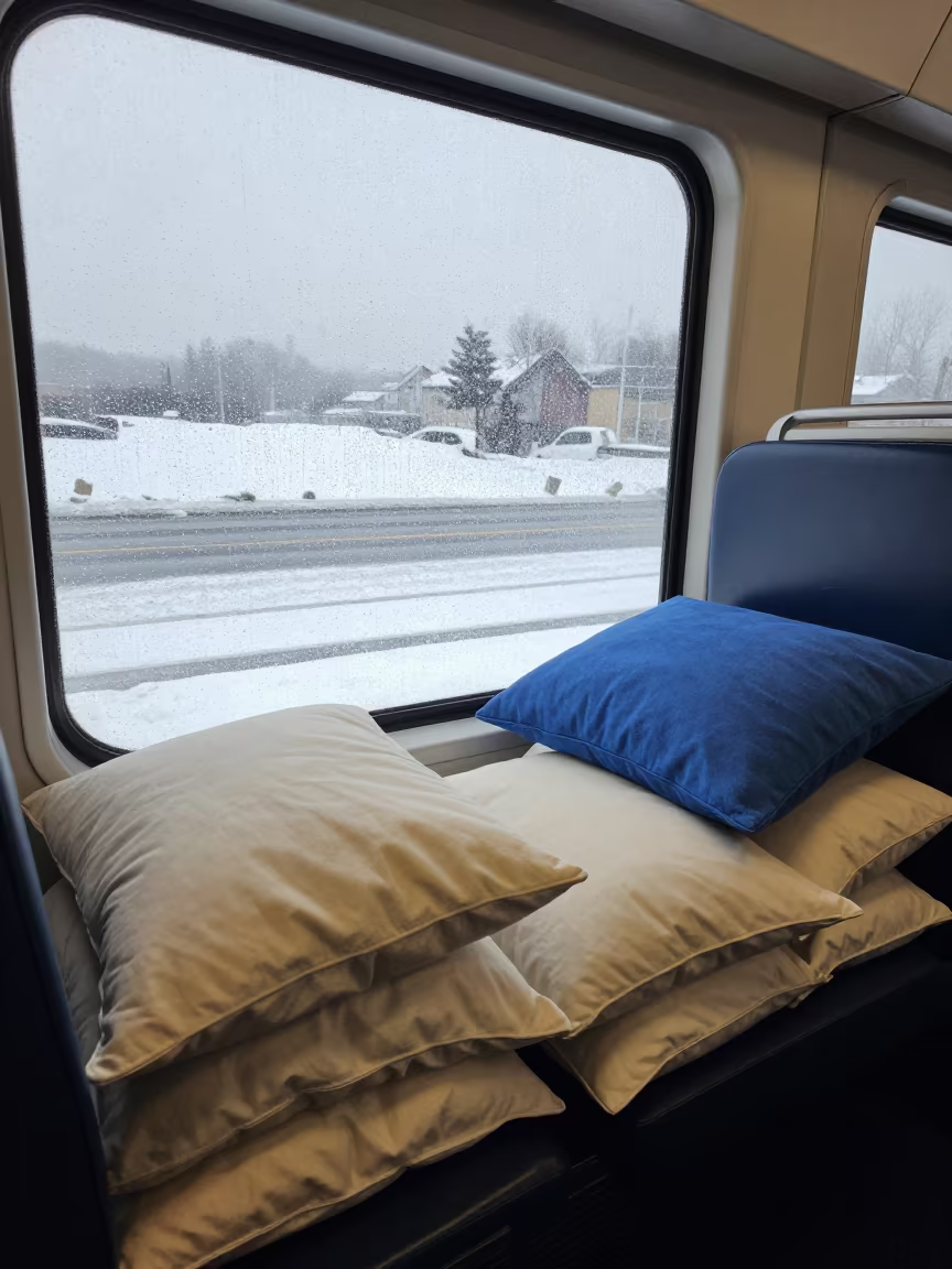 Pillow Pile on Window Seat Overlooking Snowy Lane in beside a rain-streaked window near Nawa
