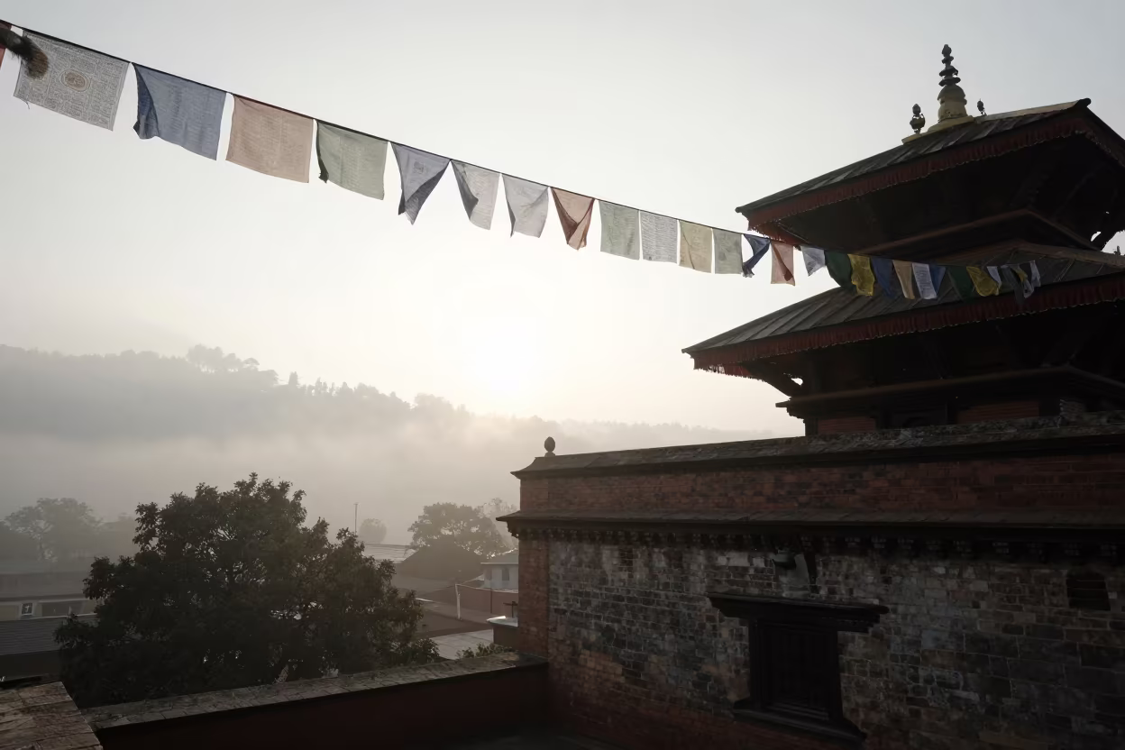 Prayer Flags Silhouetted Against Morning Mist in beside a rooftop prayer wall above the tree line near Kathmandu