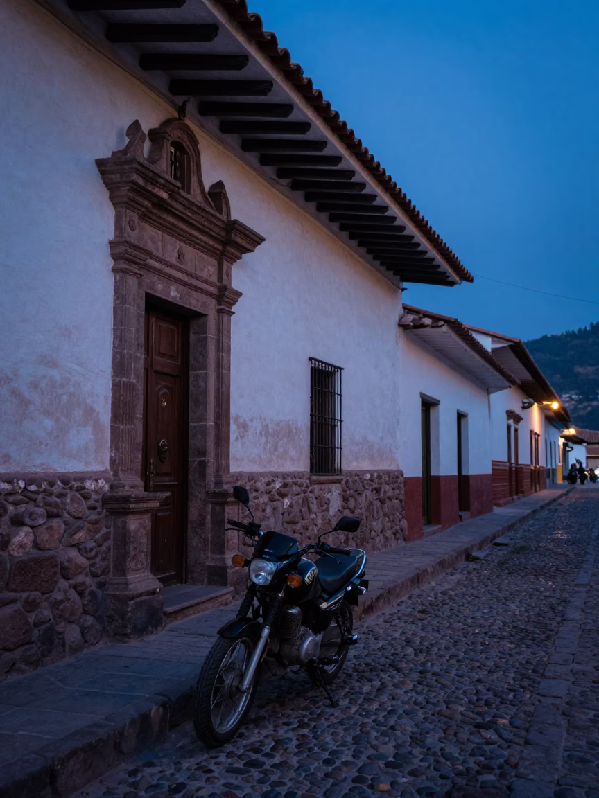 Pre-dawn Cusco street scene with motorcycle parked outside colonial stone building in in Cusco, Peru