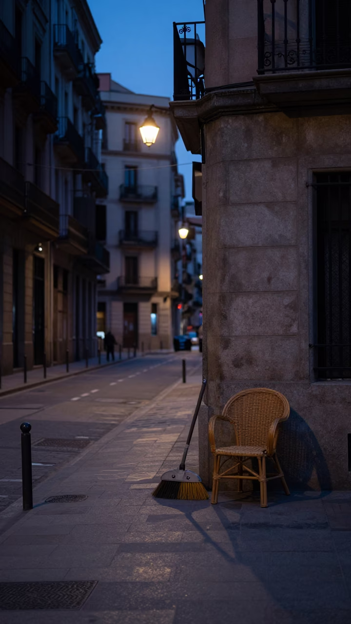 Predawn Barcelona Street Scene with Broom and Rattan Chair in Early Morning Darkness in in Barcelona, Spain